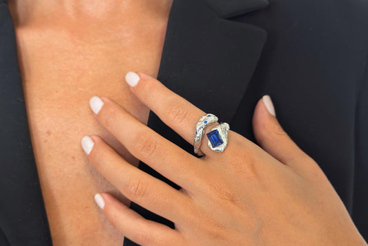 Hand wearing a ring with a blue zircon gemstone.