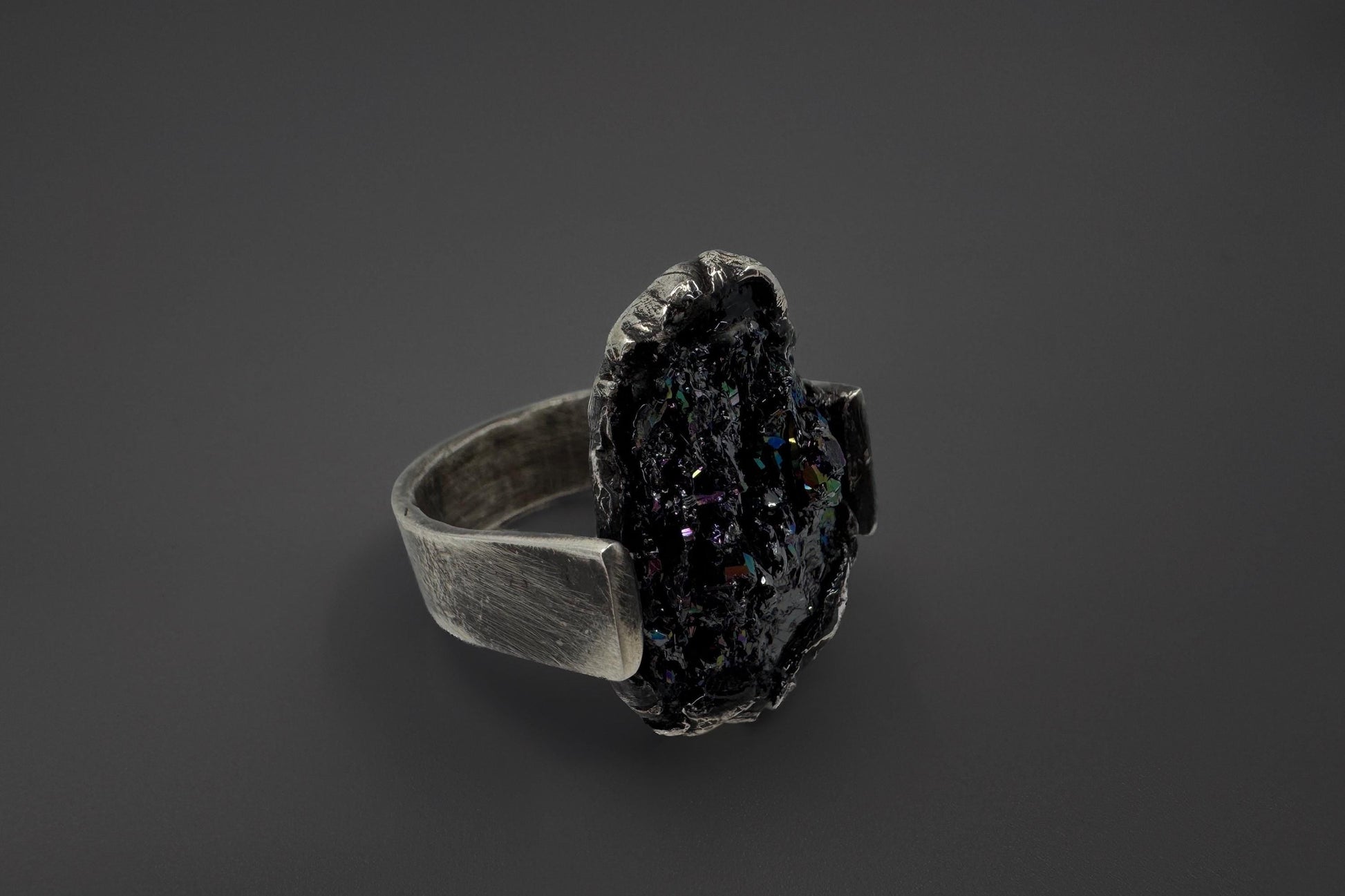 Silver ring with a dark stone on a black background